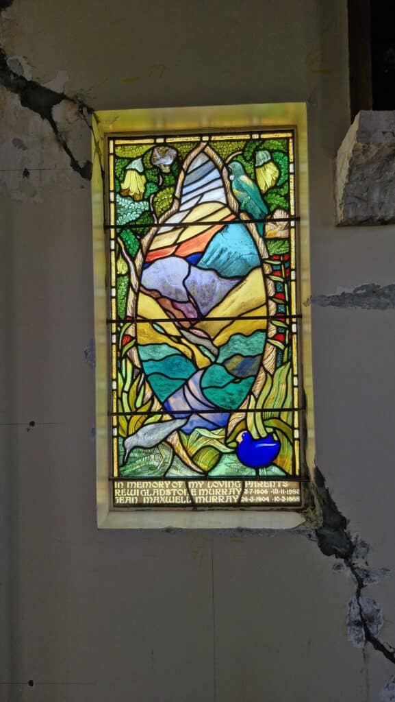 Colorful stained glass memorial window in historic Saint Oswald's heritage church, featuring vibrant botanical designs and decorative leadwork typical of classic chapel architecture.