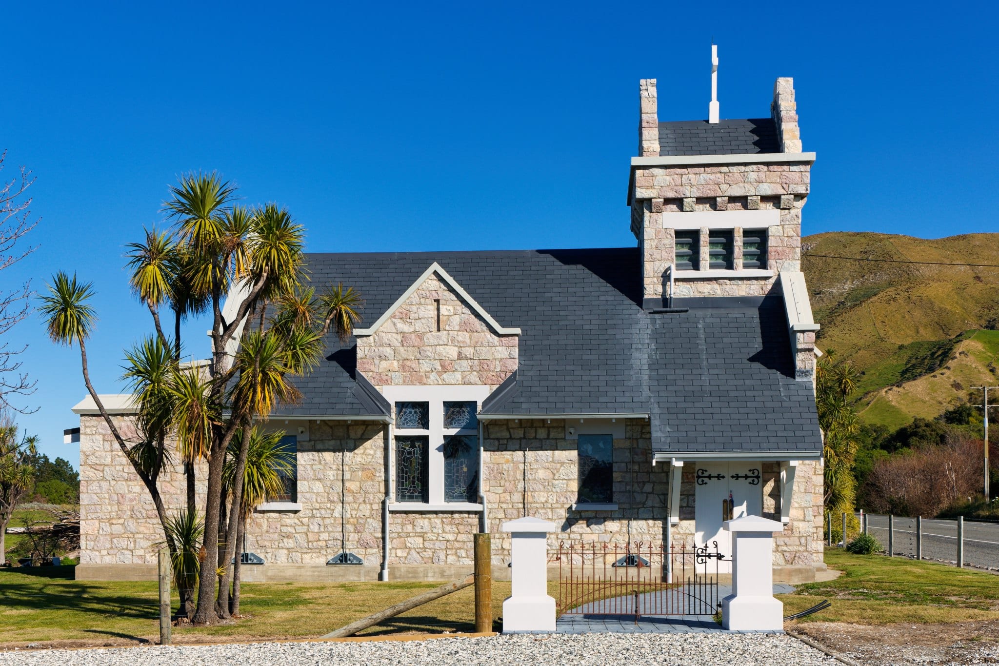 Historic stone chapel with tower, white trim, and palm trees—an elegant heritage wedding venue for ceremonies