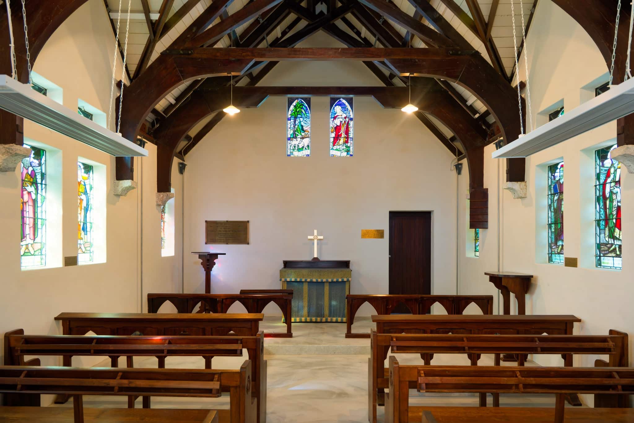 Historic Saint Oswald's Memorial Church interior with wooden pews, vaulted timber ceiling, stained glass windows, and altar—an elegant heritage wedding venue for intimate ceremonies.