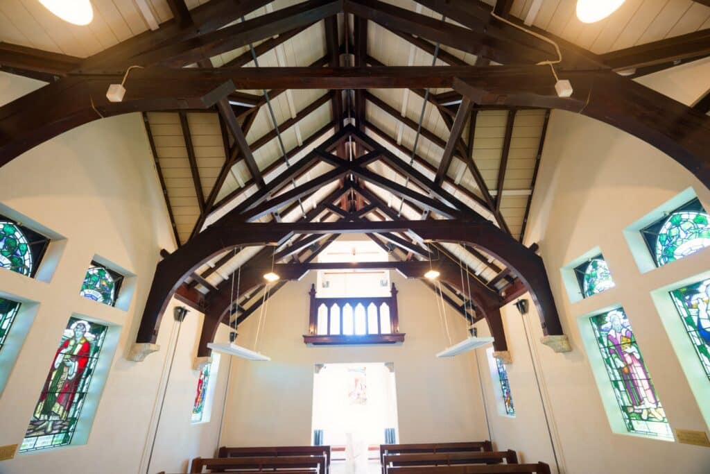 Historic church interior with exposed timber beams, stained glass windows, wooden pews, and elegant heritage architecture perfect for wedding ceremonies