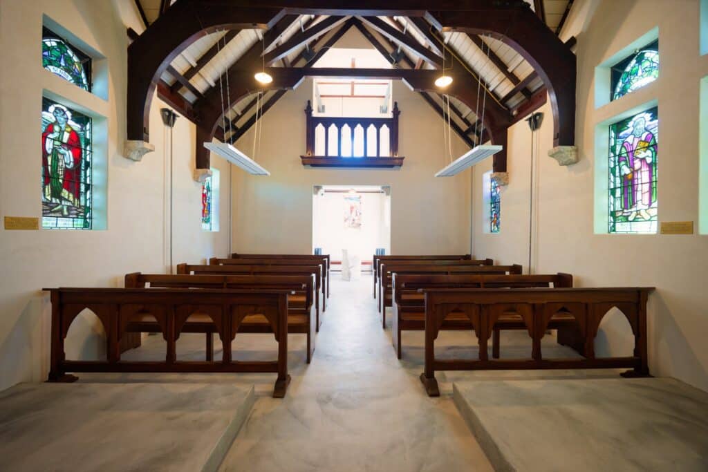 Historic Saint Oswald's Memorial Church chapel interior with wooden pews, stained glass windows, vaulted ceiling and altar&mdash;an elegant heritage wedding venue for intimate ceremonies.