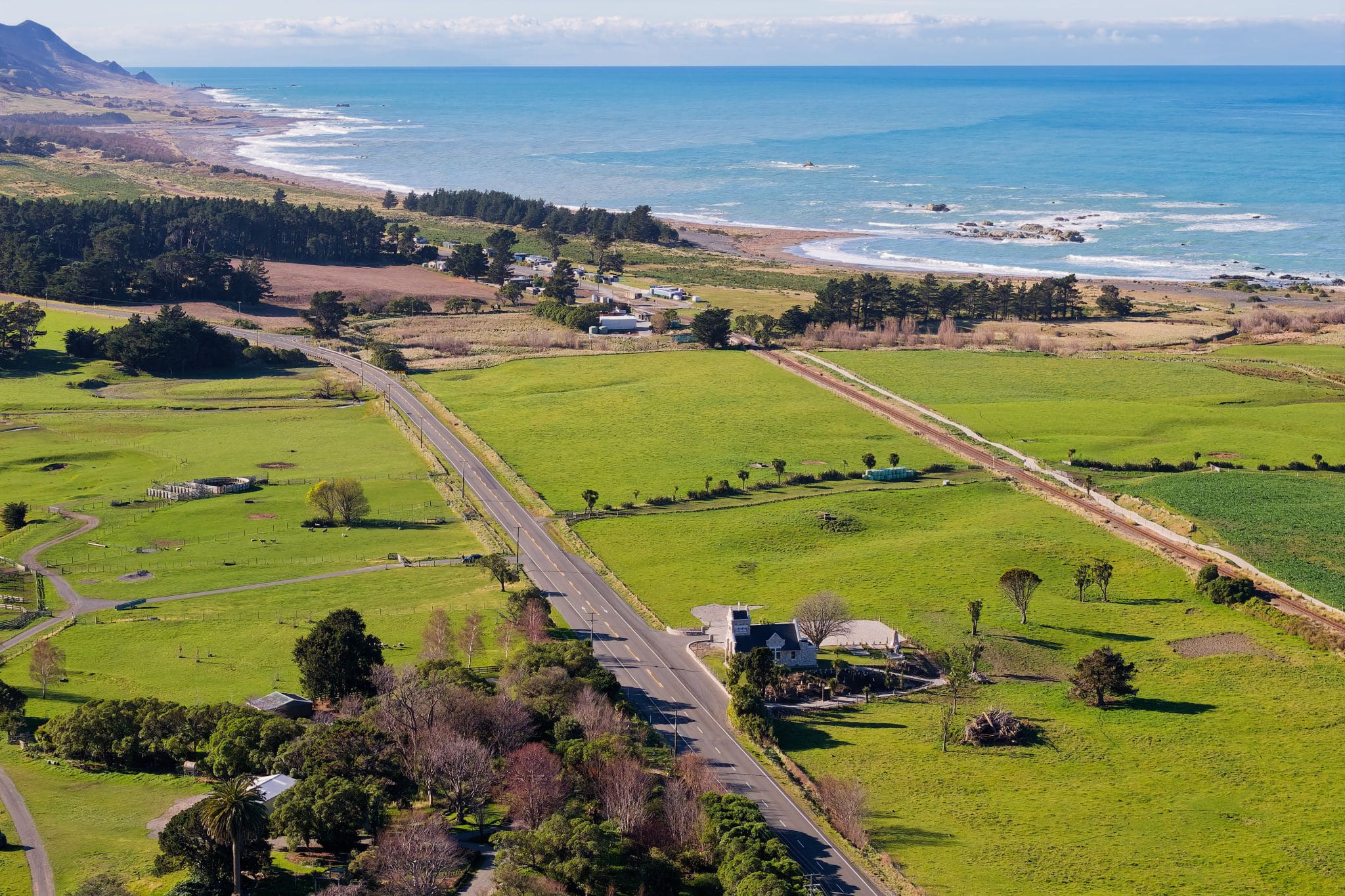 Aerial view of lush green farmland leading to coastal cliffs and ocean, ideal heritage wedding venue backdrop with scenic countryside charm