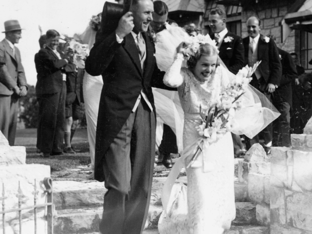 Historic wedding ceremony at heritage church with bride and groom celebrating outside stone chapel building surrounded by guests