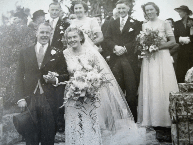 Bride and groom smile after their ceremony at historic Saint Oswald's Memorial Church, surrounded by wedding guests in traditional formal attire